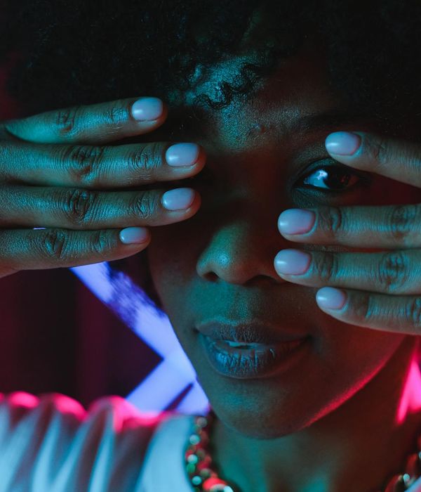 Woman performing a gentle yoga pose in a calm, dark environment with pink light.